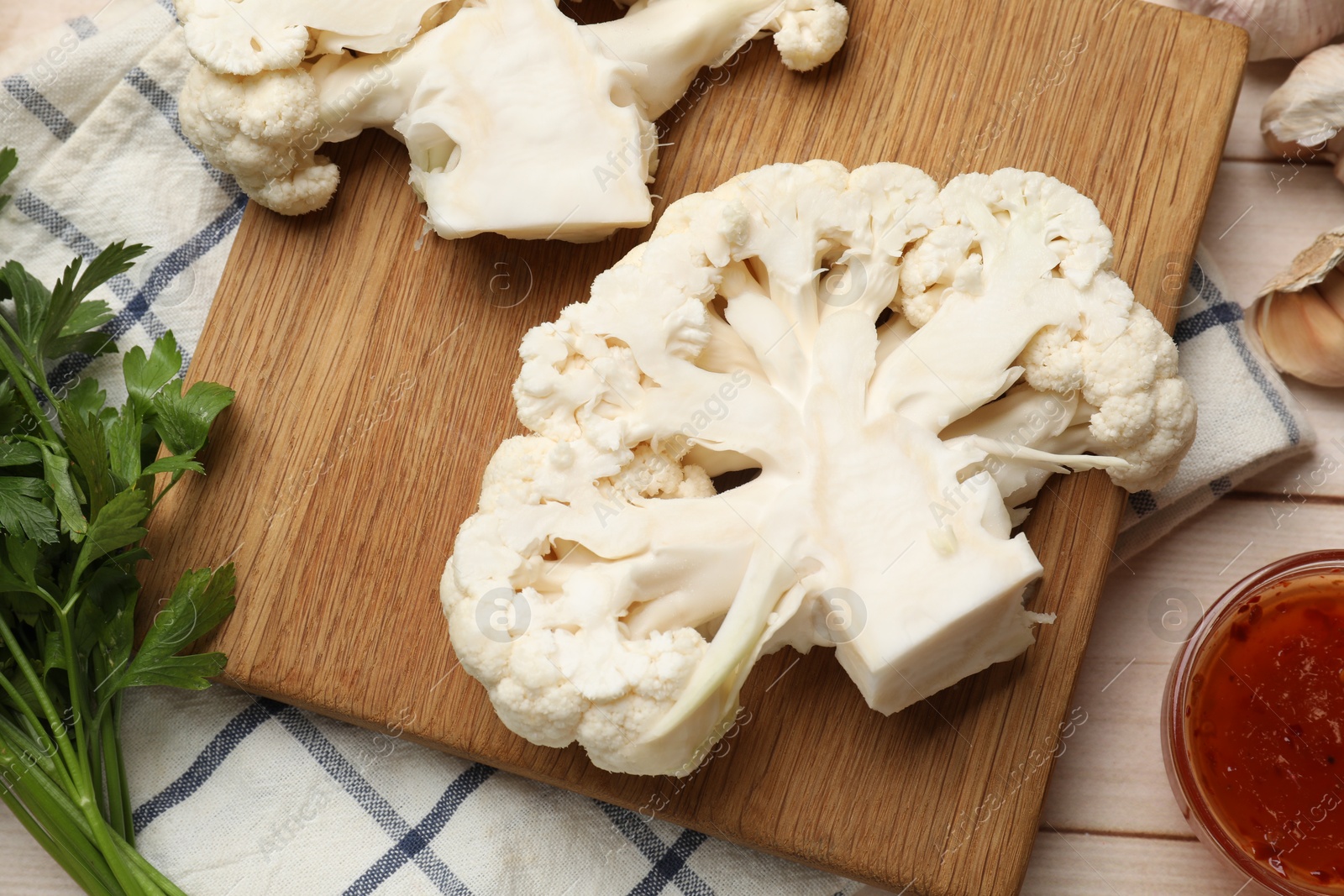 Photo of Uncooked cauliflower steaks, sauce and spices on table, flat lay