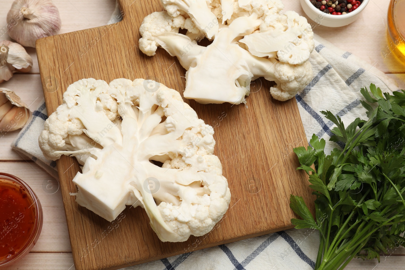 Photo of Uncooked cauliflower steaks, sauce and spices on wooden table, flat lay