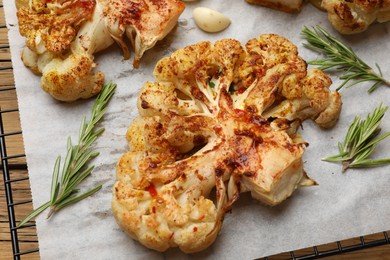 Photo of Tasty cauliflower steaks, rosemary and garlic on table, closeup