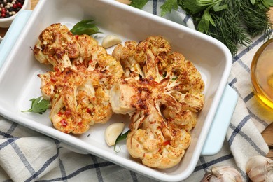 Photo of Tasty cauliflower steaks in baking dish and spices on table, top view