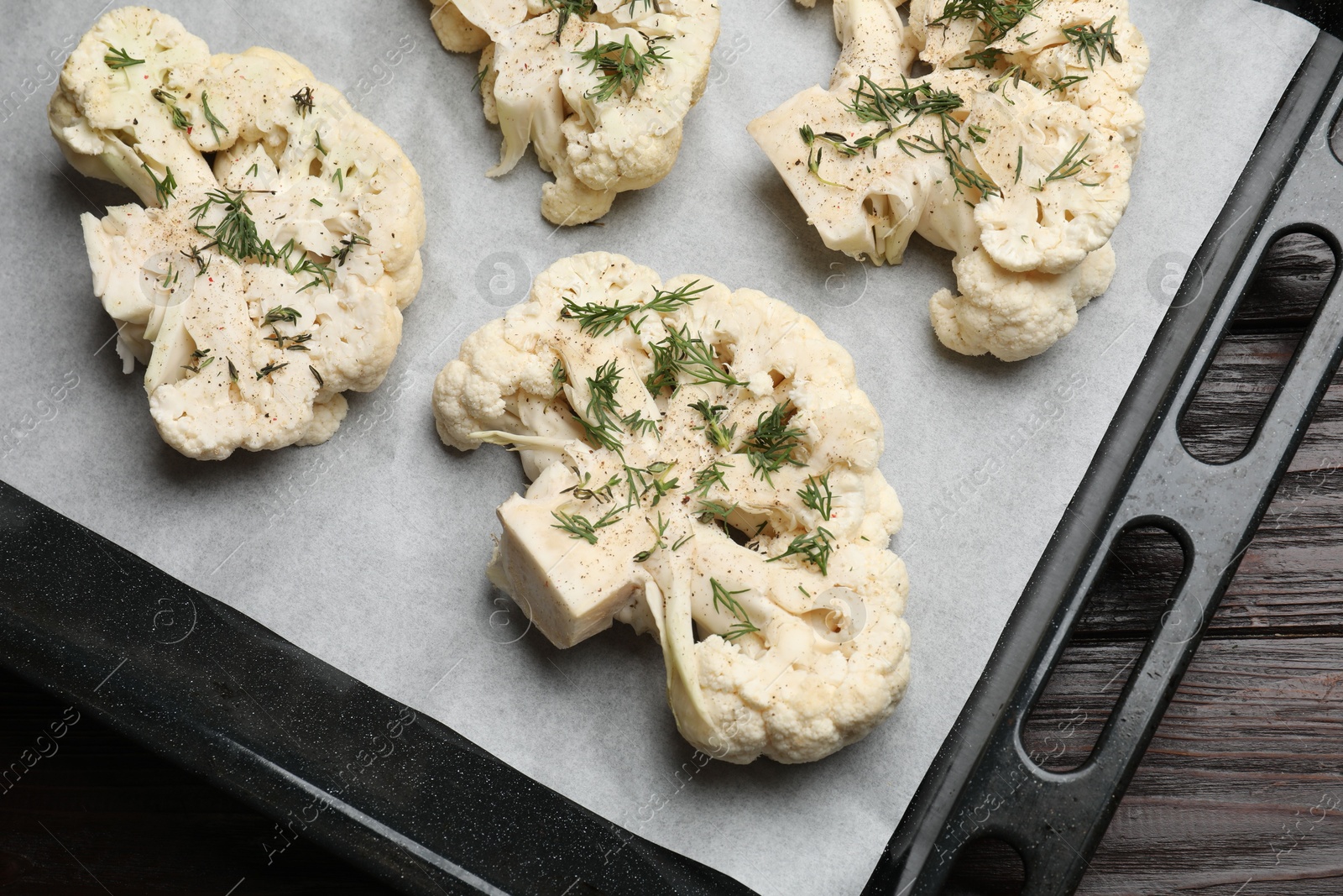 Photo of Uncooked cauliflower steaks with spices on wooden table, top view