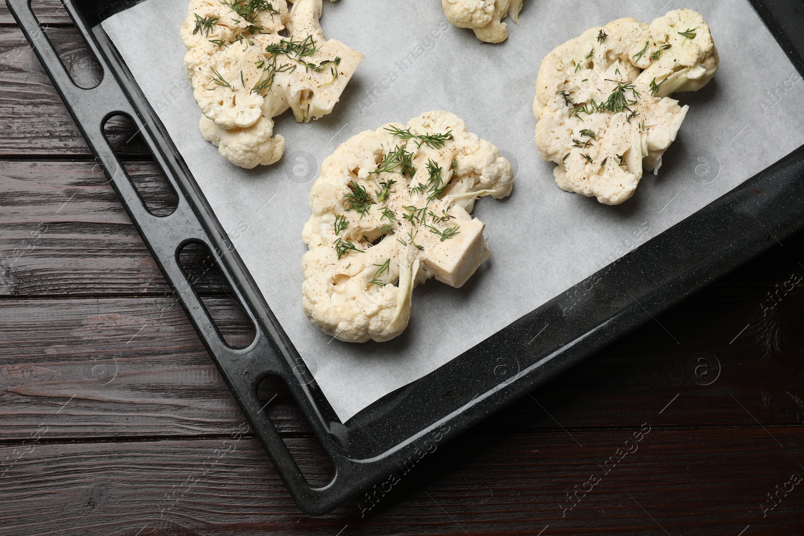 Photo of Uncooked cauliflower steaks with spices on wooden table, top view