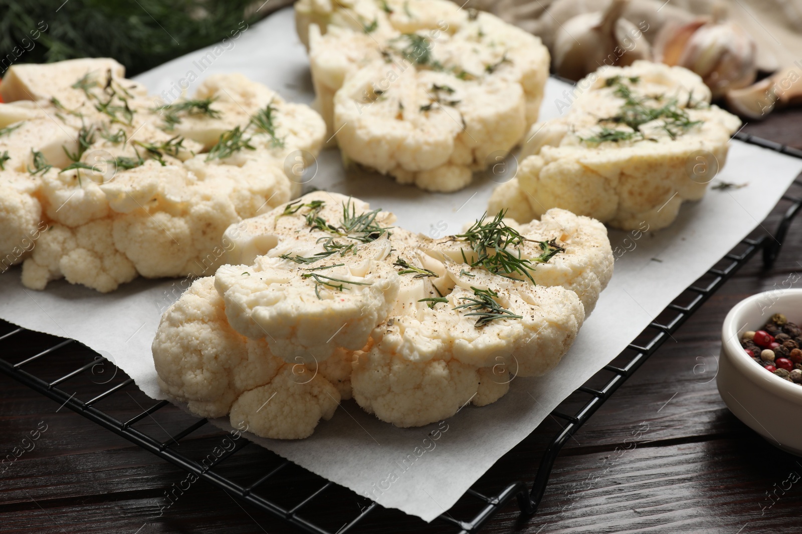 Photo of Uncooked cauliflower steaks with spices on wooden table, closeup