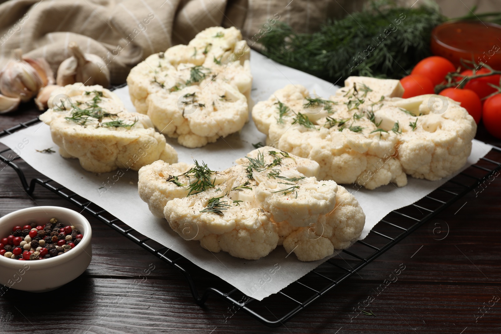 Photo of Uncooked cauliflower steaks with spices on wooden table, closeup