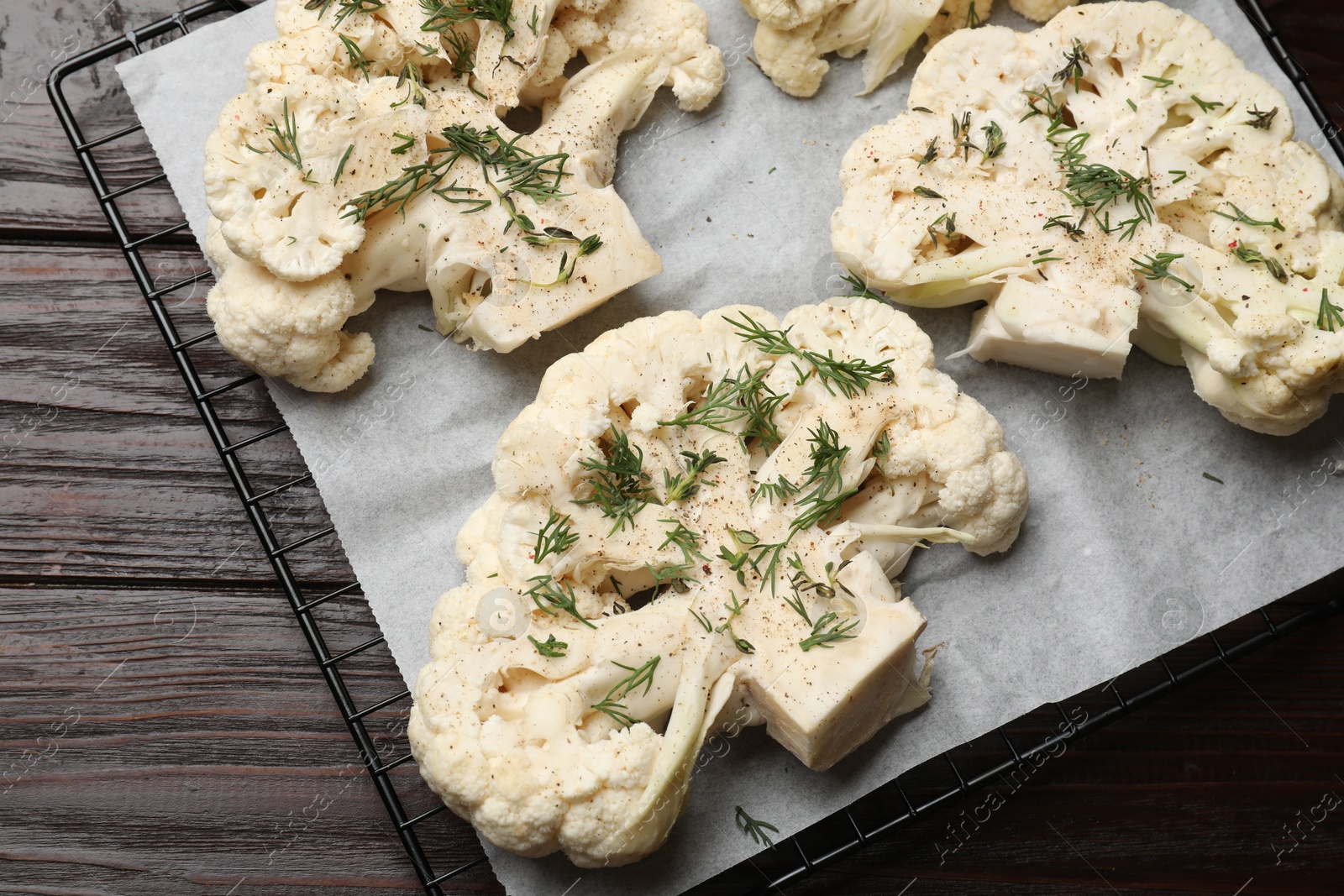 Photo of Uncooked cauliflower steaks and dill on wooden table, top view