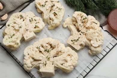 Photo of Uncooked cauliflower steaks, dill, garlic and sauce on white marble table, top view