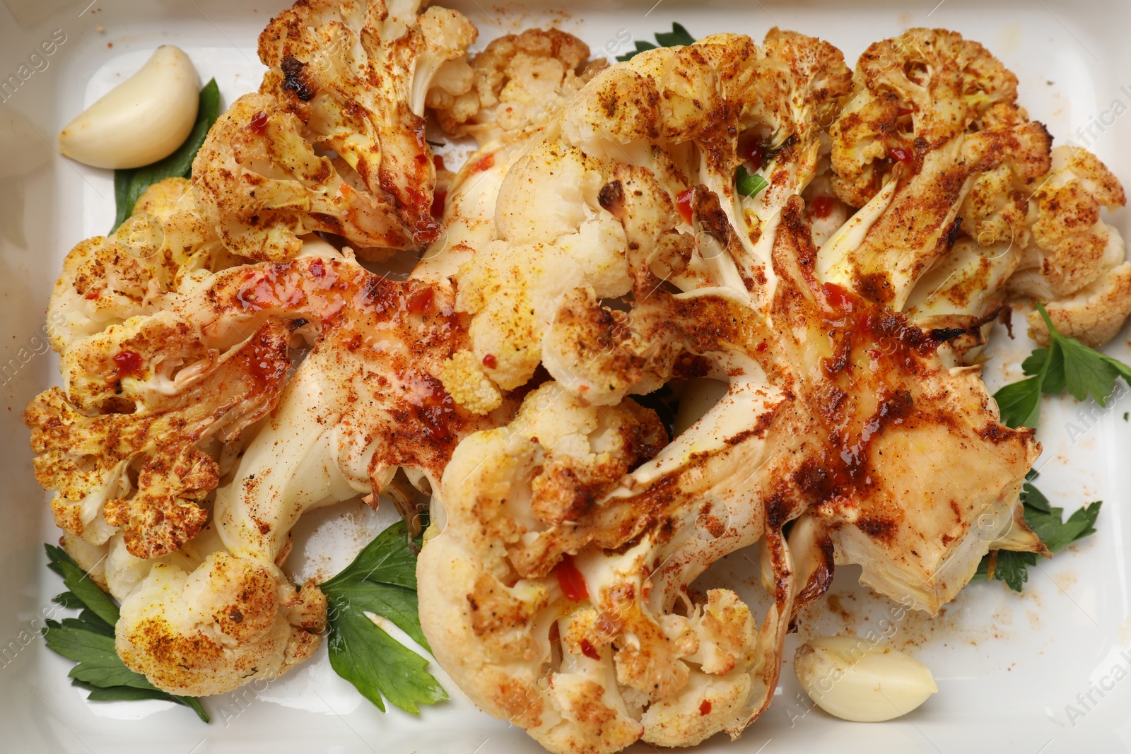 Photo of Delicious cauliflower steaks in baking dish, top view