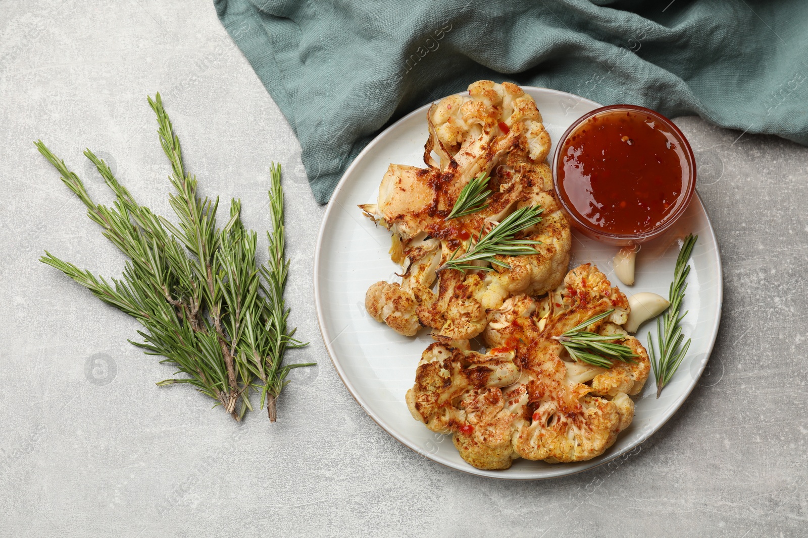 Photo of Delicious baked cauliflower steaks with sauce on grey table, top view