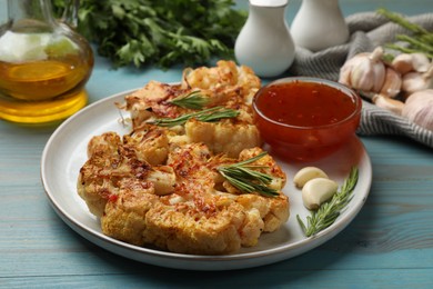 Photo of Delicious baked cauliflower steaks with sauce on blue wooden table