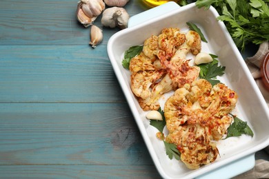 Photo of Delicious baked cauliflower steaks on blue wooden table, top view. Space for text