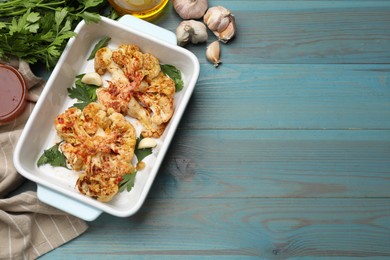 Photo of Delicious baked cauliflower steaks on blue wooden table, top view. Space for text