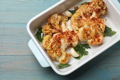 Photo of Delicious baked cauliflower steaks on blue wooden table, top view