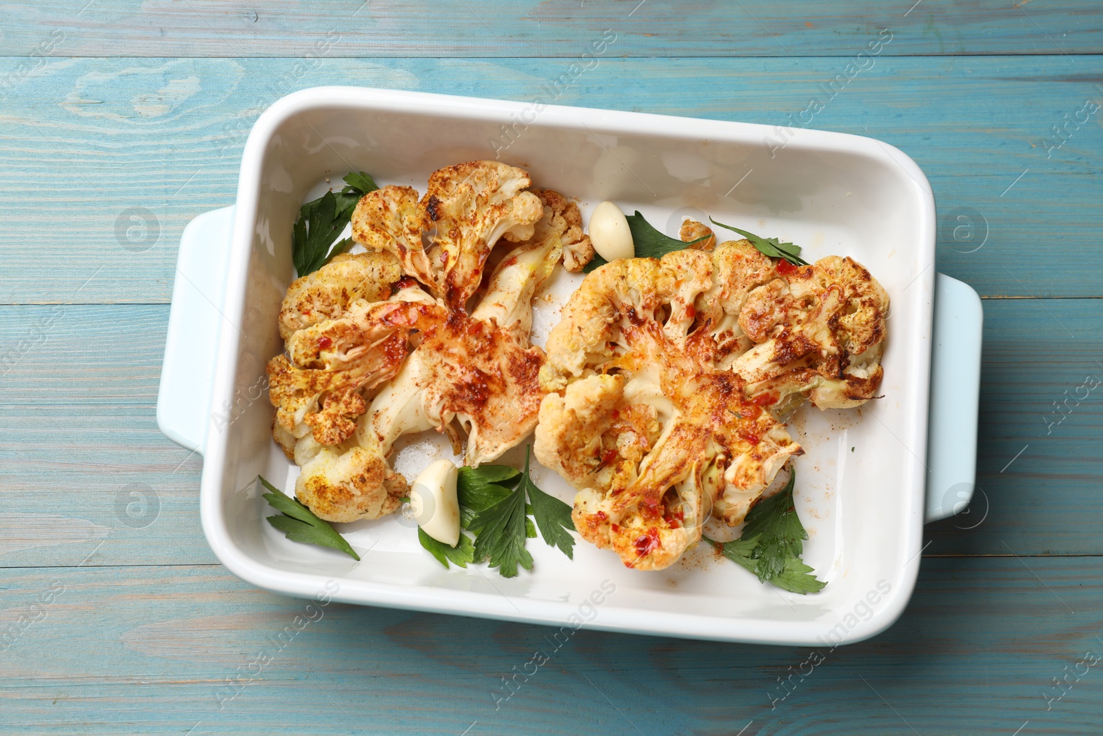 Photo of Delicious baked cauliflower steaks on blue wooden table, top view