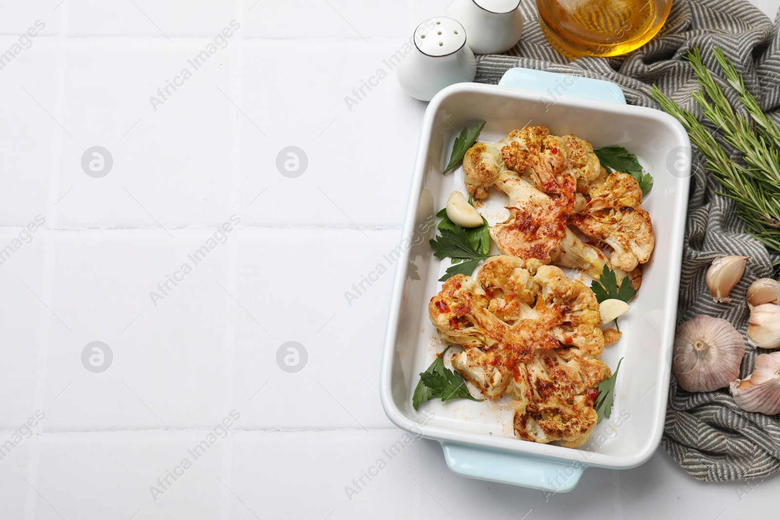 Photo of Delicious baked cauliflower steaks served on white tiled table, flat lay. Space for text