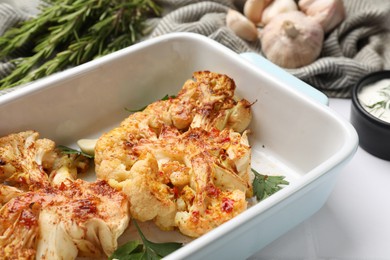 Photo of Delicious baked cauliflower steaks served on white tiled table, closeup