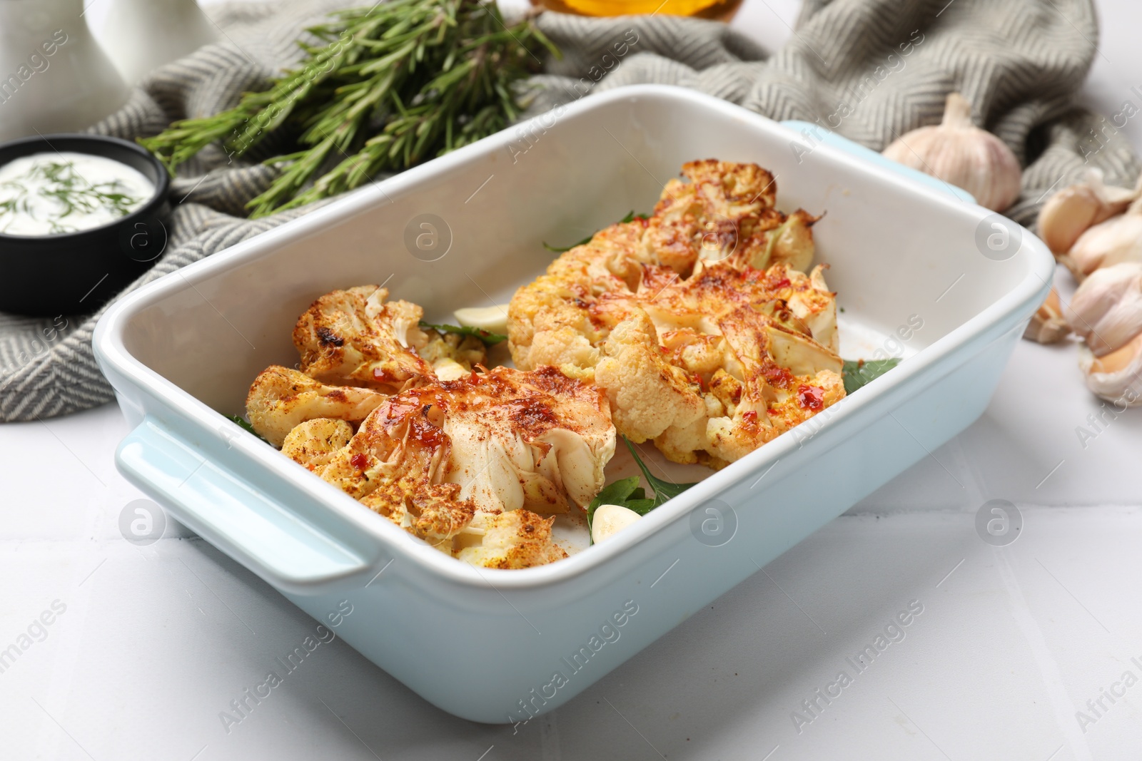 Photo of Delicious baked cauliflower steaks served on white tiled table, closeup