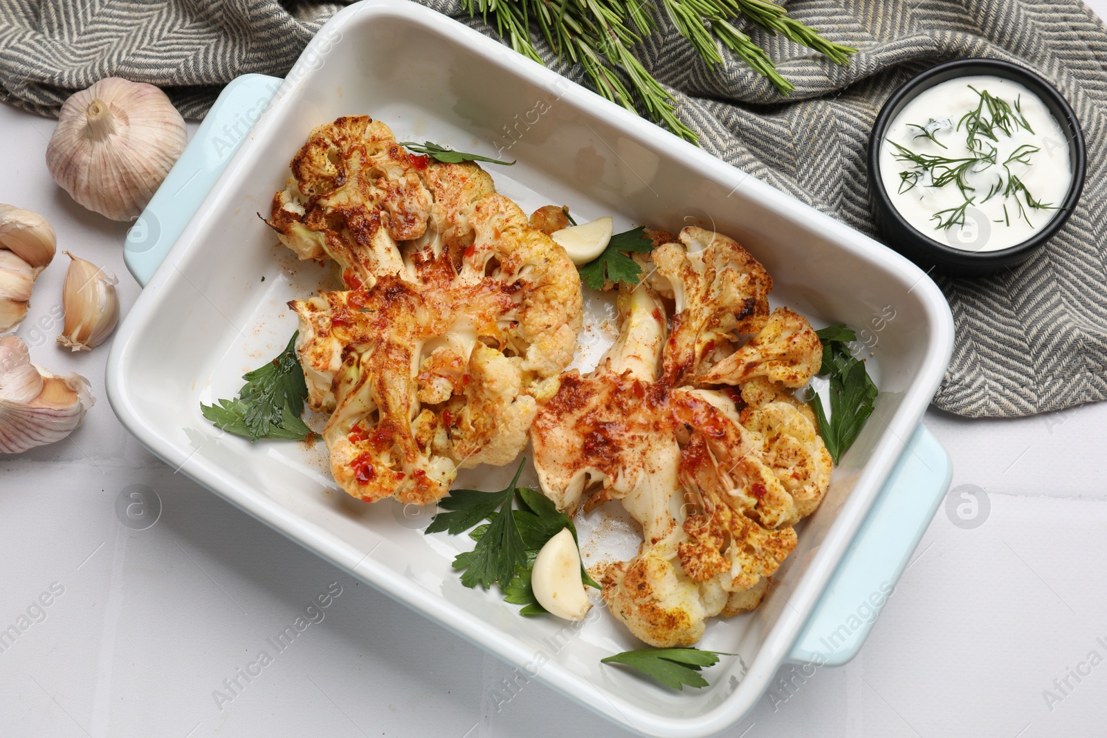 Photo of Delicious baked cauliflower steaks served on white tiled table, flat lay