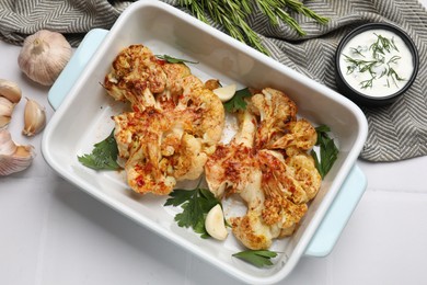 Photo of Delicious baked cauliflower steaks served on white tiled table, flat lay