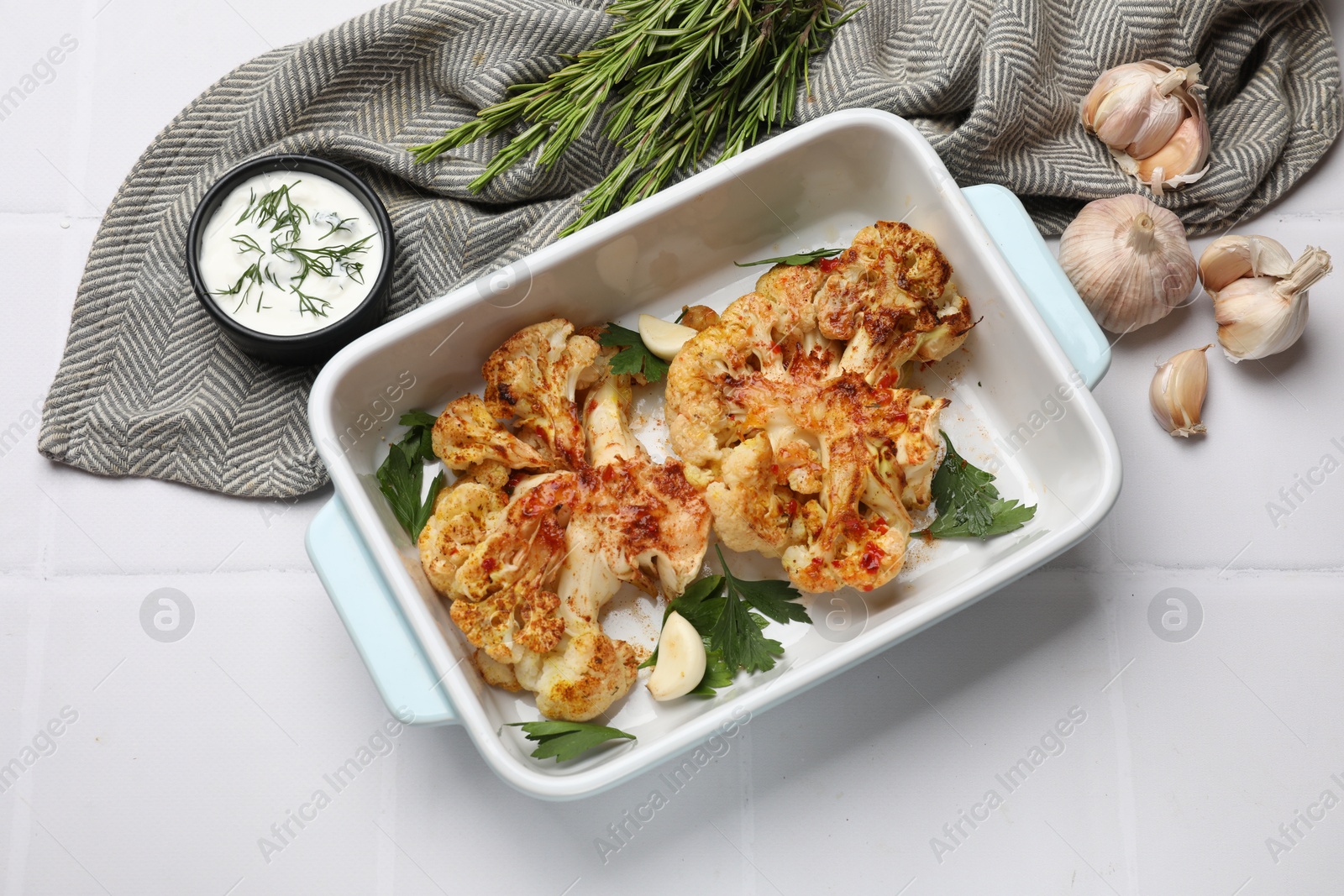 Photo of Delicious baked cauliflower steaks served on white tiled table, flat lay