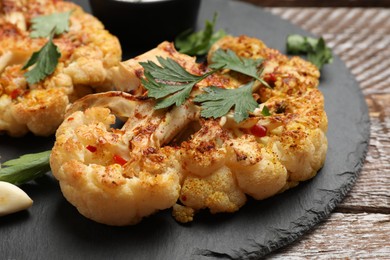 Photo of Delicious baked cauliflower steaks on wooden table, closeup