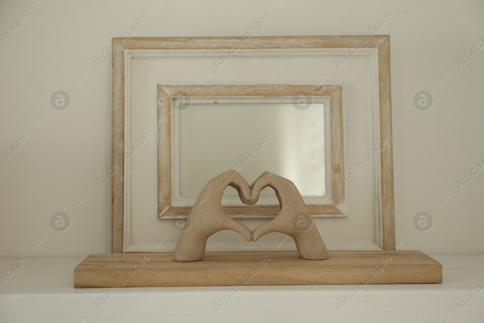 Photo of Blank picture frame with figure of hands on white shelf