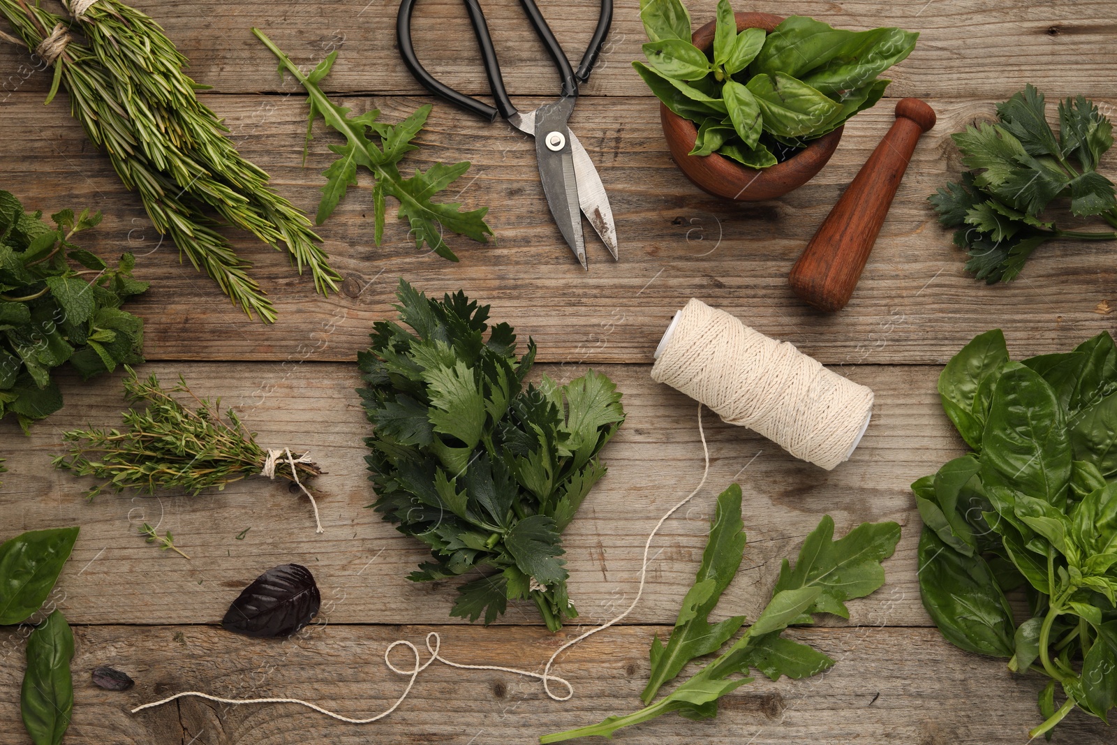 Photo of Different aromatic herbs, mortar with pestle, thread and scissors on wooden table, flat lay