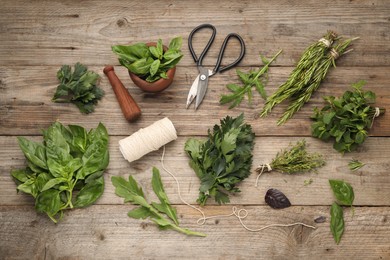 Photo of Different aromatic herbs, mortar with pestle, thread and scissors on wooden table, flat lay