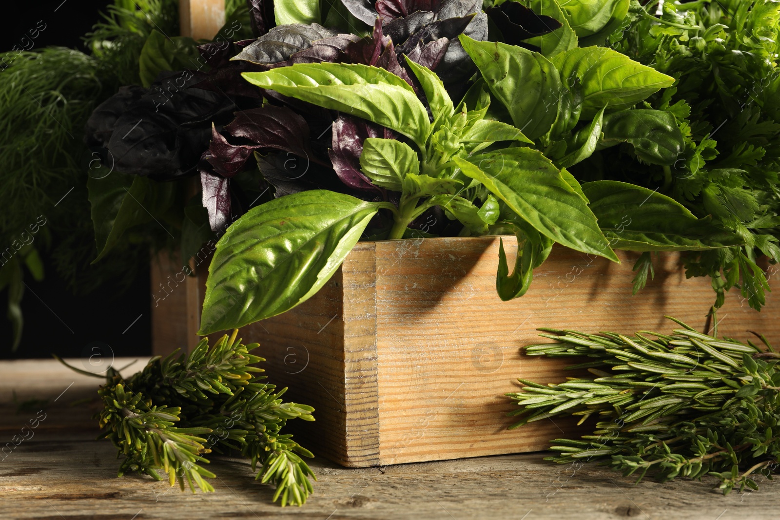 Photo of Different aromatic herbs in crate on wooden table, closeup