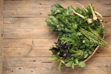 Photo of Different aromatic herbs in wicker basket on wooden table, top view. Space for text