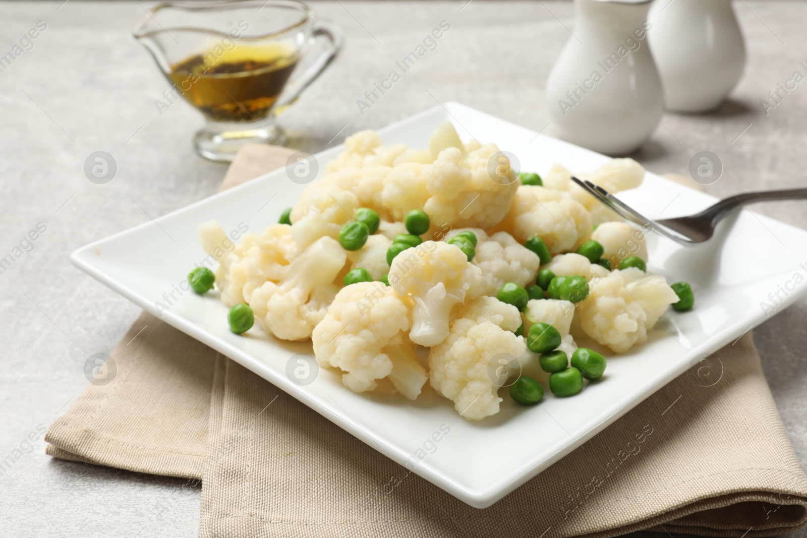 Photo of Tasty cooked cauliflower with green peas on grey table, closeup