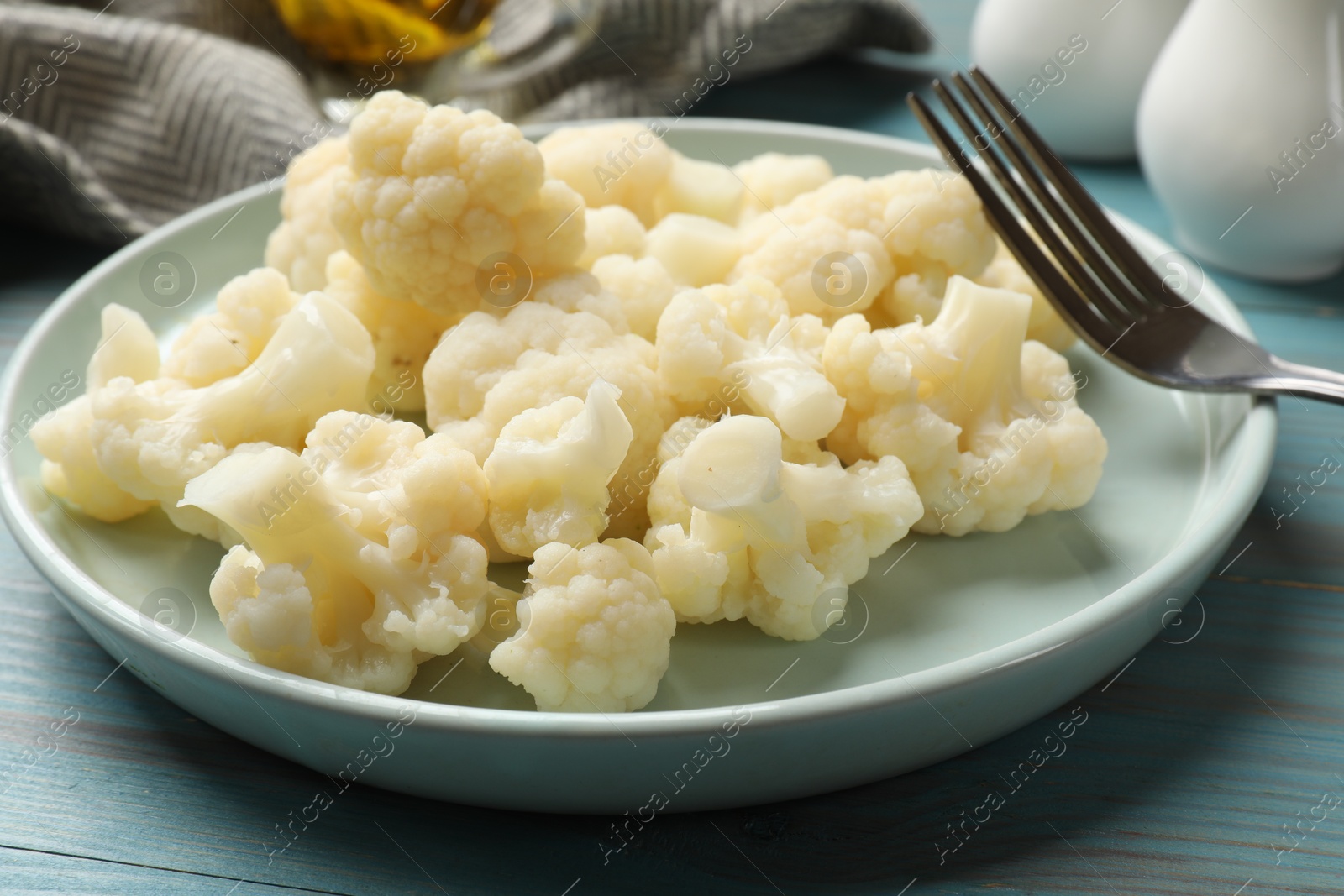 Photo of Tasty cooked cauliflower on light blue wooden table, closeup