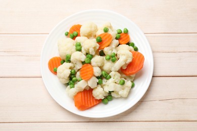 Photo of Tasty cooked cauliflower with green peas and carrot slices on white wooden table, top view