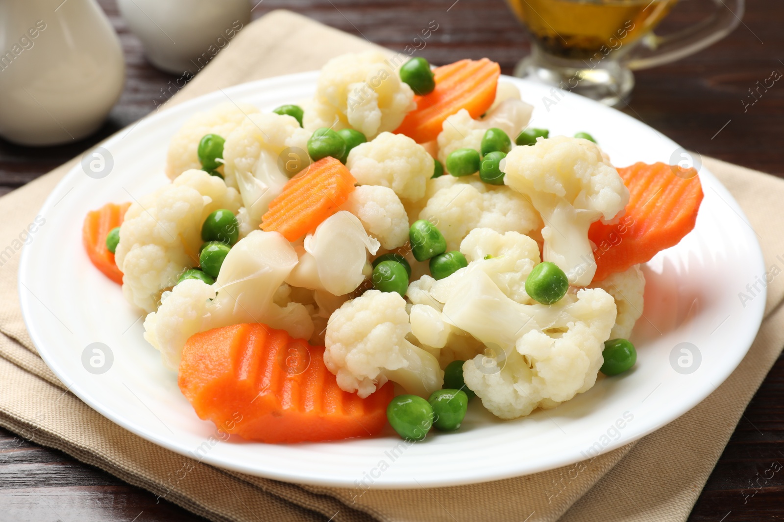 Photo of Tasty cooked cauliflower with green peas and carrot slices on white wooden table, closeup