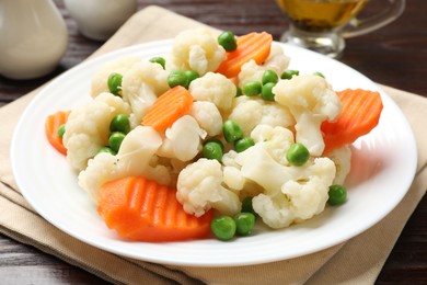 Photo of Tasty cooked cauliflower with green peas and carrot slices on white wooden table, closeup