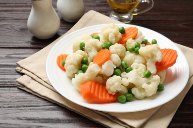 Photo of Tasty cooked cauliflower with green peas and carrot slices on white wooden table, closeup