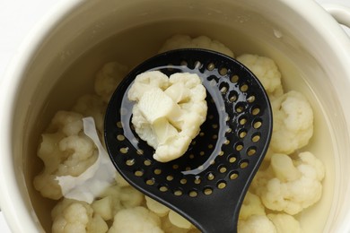 Photo of Taking away boiled cauliflower from pot with skimmer, closeup