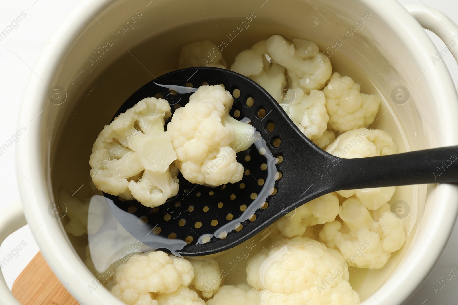 Photo of Taking away boiled cauliflower from pot with skimmer, closeup