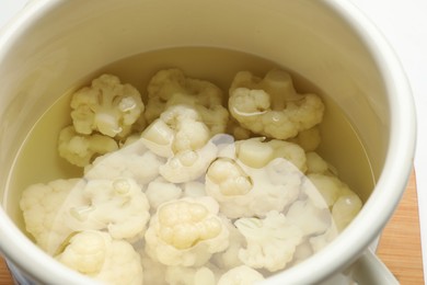 Photo of Cauliflower in pot with water on table, closeup