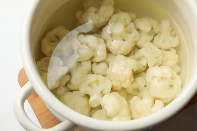 Photo of Cauliflower in pot with water on table, closeup