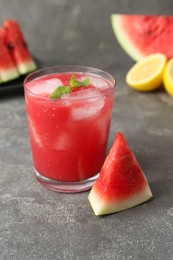 Photo of Tasty watermelon drink in glass, fresh fruits and mint on grey table