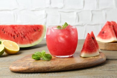 Photo of Tasty watermelon drink in glass, mint and fresh fruits on wooden table