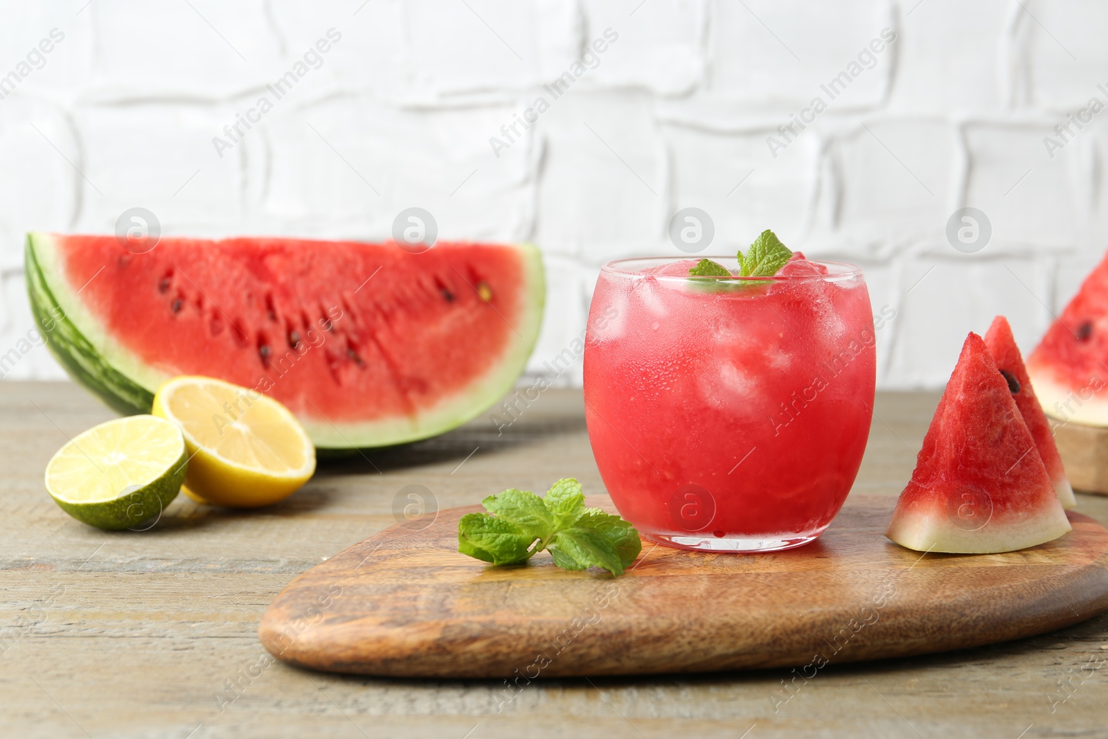 Photo of Tasty watermelon drink in glass, mint and fresh fruits on wooden table