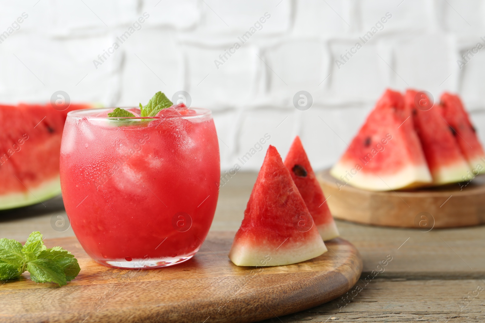 Photo of Tasty watermelon drink in glass, mint and fresh fruits on wooden table