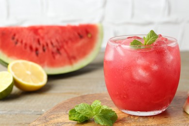 Photo of Tasty watermelon drink in glass, mint and fresh fruits on wooden table, closeup