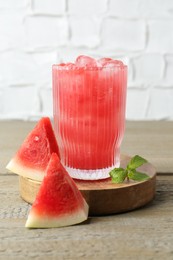 Photo of Tasty watermelon drink in glass, mint and fresh fruit on wooden table