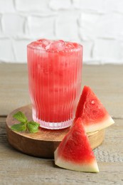 Photo of Tasty watermelon drink in glass, mint and fresh fruit on wooden table