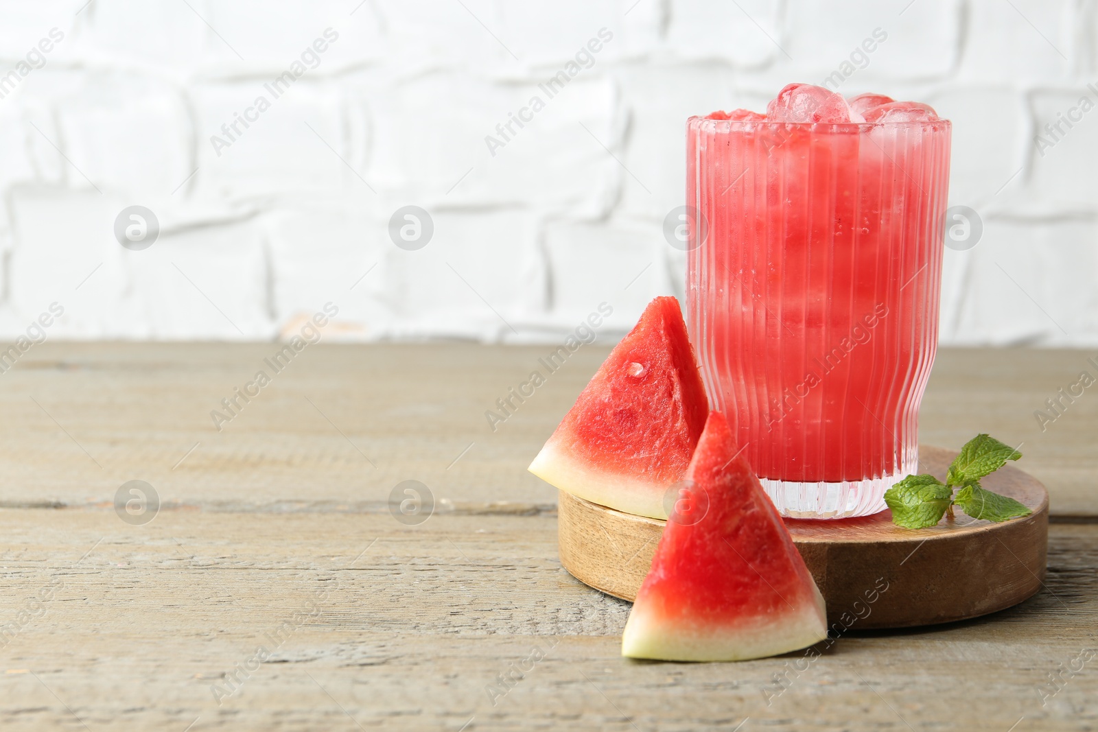 Photo of Tasty watermelon drink in glass, mint and fresh fruit on wooden table, space for text