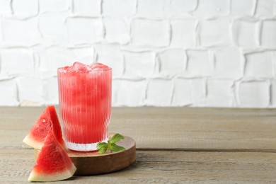 Photo of Tasty watermelon drink in glass, mint and fresh fruit on wooden table, space for text