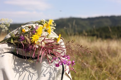 Photo of Bouquet of beautiful flowers and backpack outdoors, closeup. Space for text