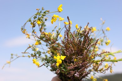 Photo of Woman holding bouquet of wild flowers outdoors, closeup